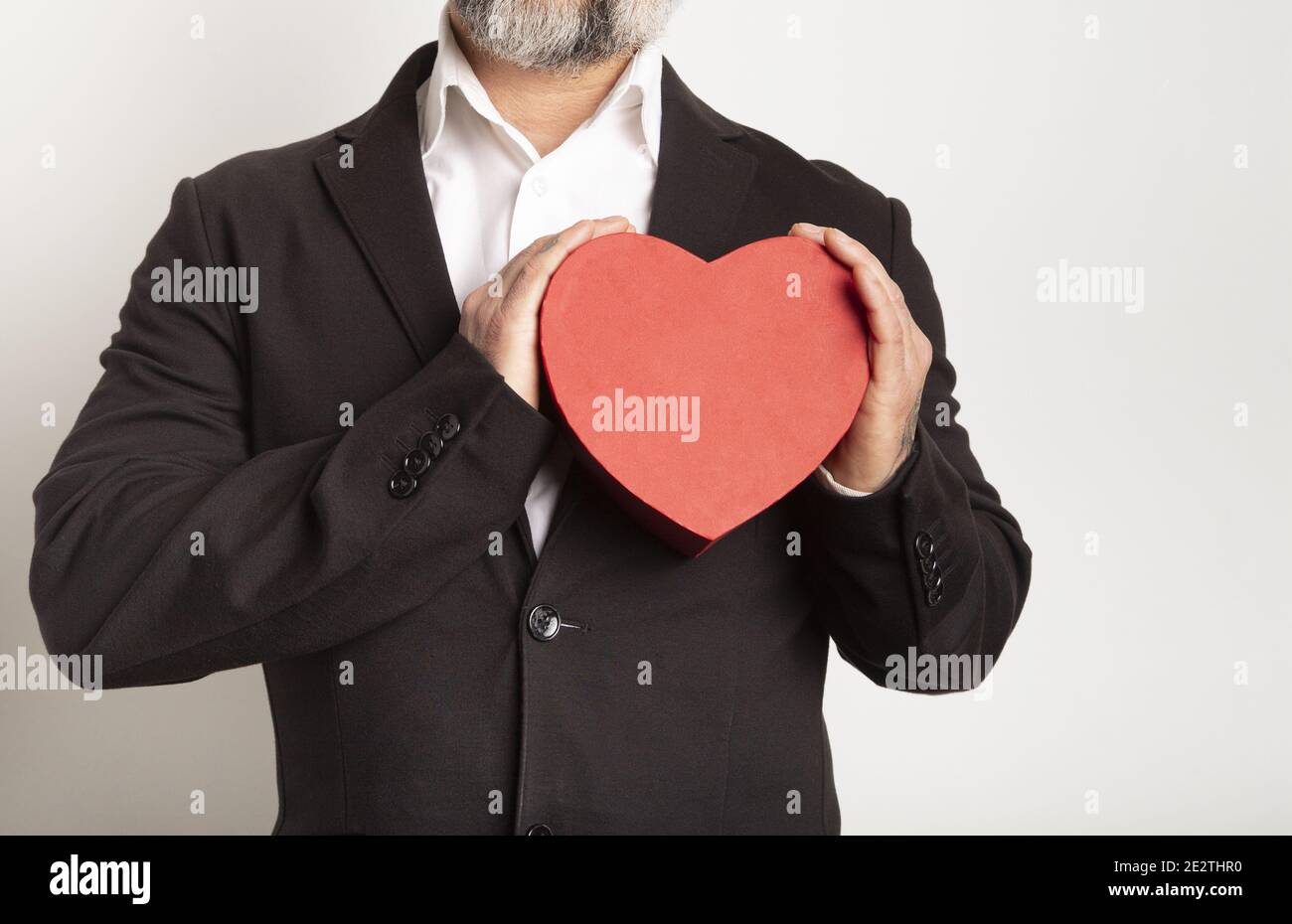 Geschäftsmann in Anzug gekleidet und hält ein rotes Herz auf weißem Hintergrund. Valentinstag Stockfoto