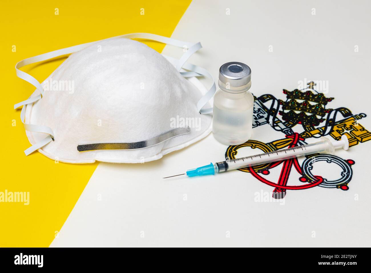 Vatikanstadt Staatsflagge, N95 Gesichtsmaske, Nadelspritze und Fläschchen. Konzept der Covid-19 Coronavirus-Impfstoffverteilung, Versorgungsengpässe und Gesundheitsversorgung Stockfoto