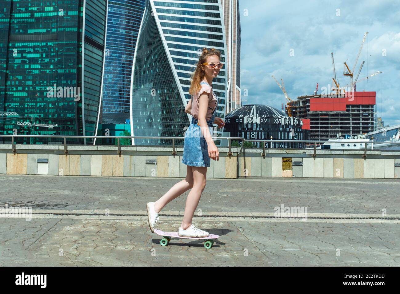 Schlanke Mädchen Teenager reitet ein Skateboard in der Stadt auf Ein sonniger Sommertag Stockfoto