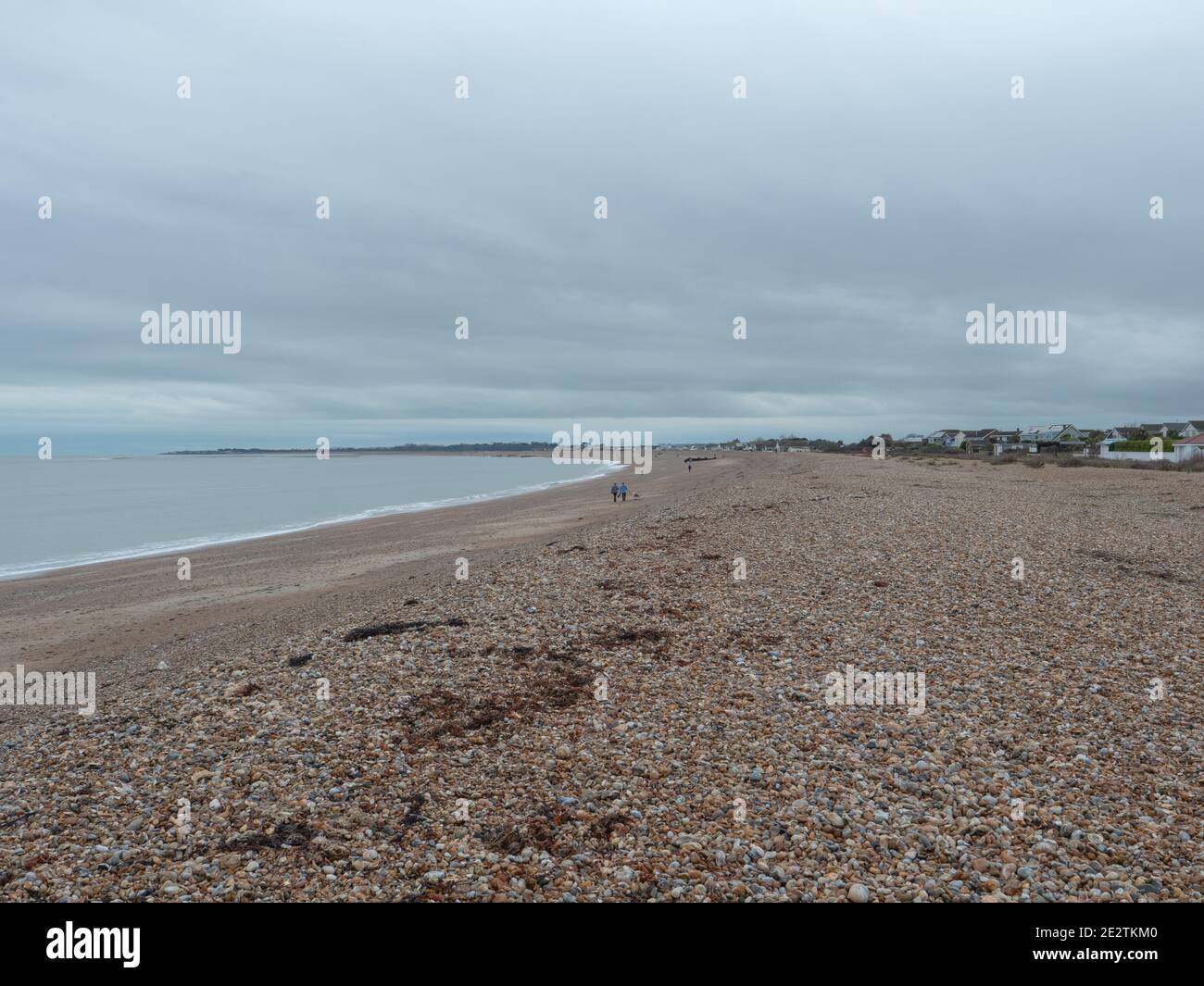 Leerer Strand mit einigen Leuten, die entlang der Uferlinie von Aldwick in der Nähe von Bognor Regis, England laufen. Stockfoto