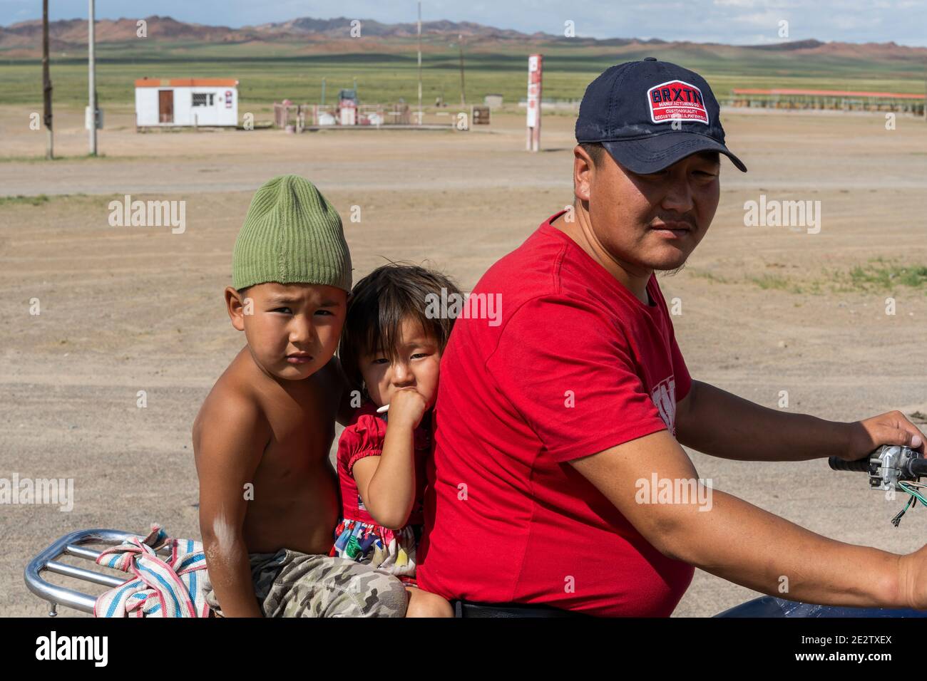 Olgii, Mongolei - 7. August 2019: Familie auf dem Motorrad mit zwei kleinen Kindern in der Steppe der Mongolei. Stockfoto