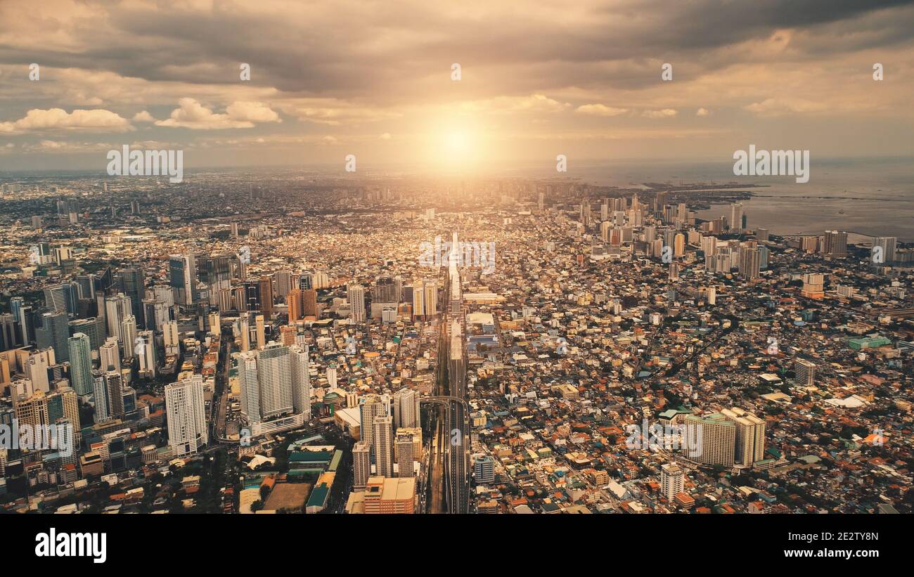 Sonne über den Dächern der Stadt Wolkenkratzer Gebäude aus der Luft. Städtische Verkehrsstraße auf Straßen der Innenstadt. Philipines Hauptstadt Stadtbild bei Sommersonne. Filipino Stadt filmischen weichen Licht Drohne erschossen Stockfoto