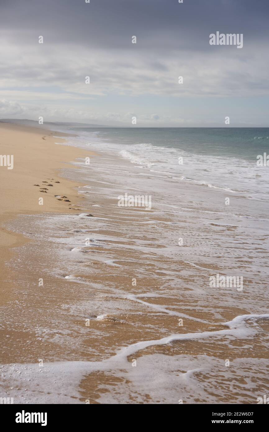 Wilder leerer Strand mit Schritten auf dem Sand und Wellen auf dem Sand in Comporta, Portugal Stockfoto