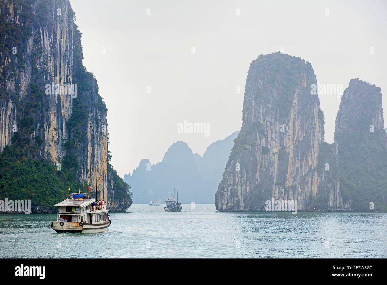 Touristische Boote und Kalkstein monolithischen Inseln in Ha Long Bay / Halong Bay / Vinh Ha Long im Nebel, Quang Ninh Provinz, Vietnam Stockfoto