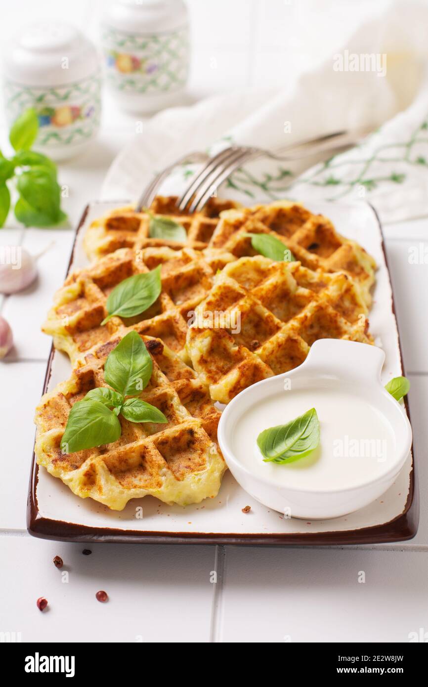 Hausgemachte Zucchini Waffeln mit Käse, Sause und Blatt Basilikum auf weißem Hintergrund. Konzept der Keto Ernährung Lebensmittel. Selektiver Fokus. Stockfoto