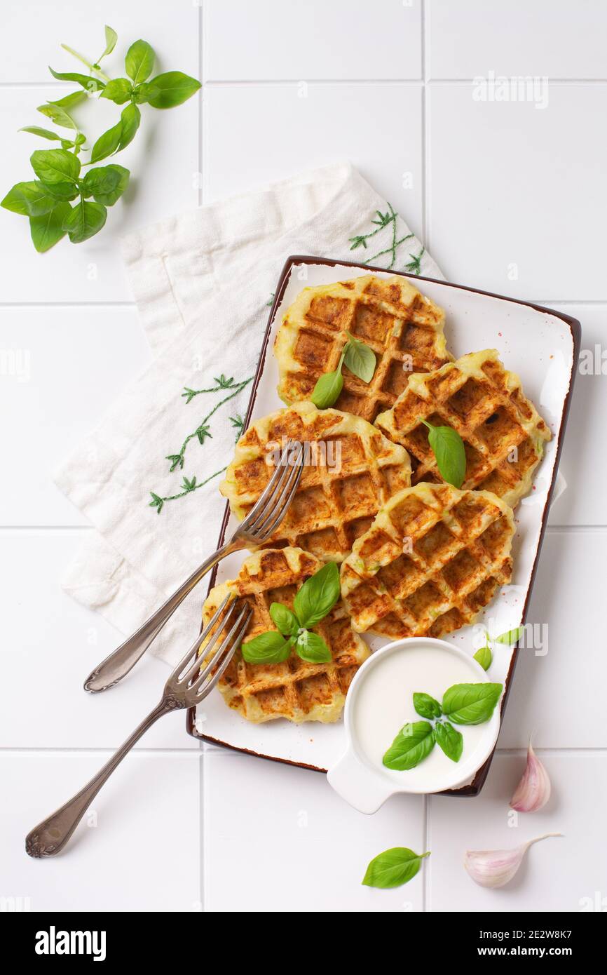 Hausgemachte Zucchini Waffeln mit Käse, Sause und Blatt Basilikum auf weißem Hintergrund. Konzept der Keto Ernährung Lebensmittel. Selektiver Fokus. Stockfoto