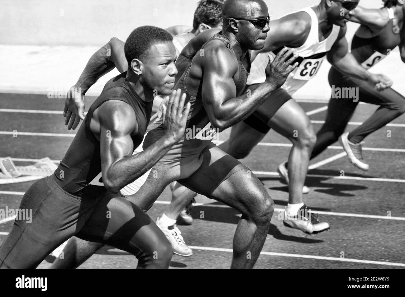 Schwarz-Weiß-Foto von Läuferinnen und Läufern, die auf der Laufschiene laufen Ein Stockfoto