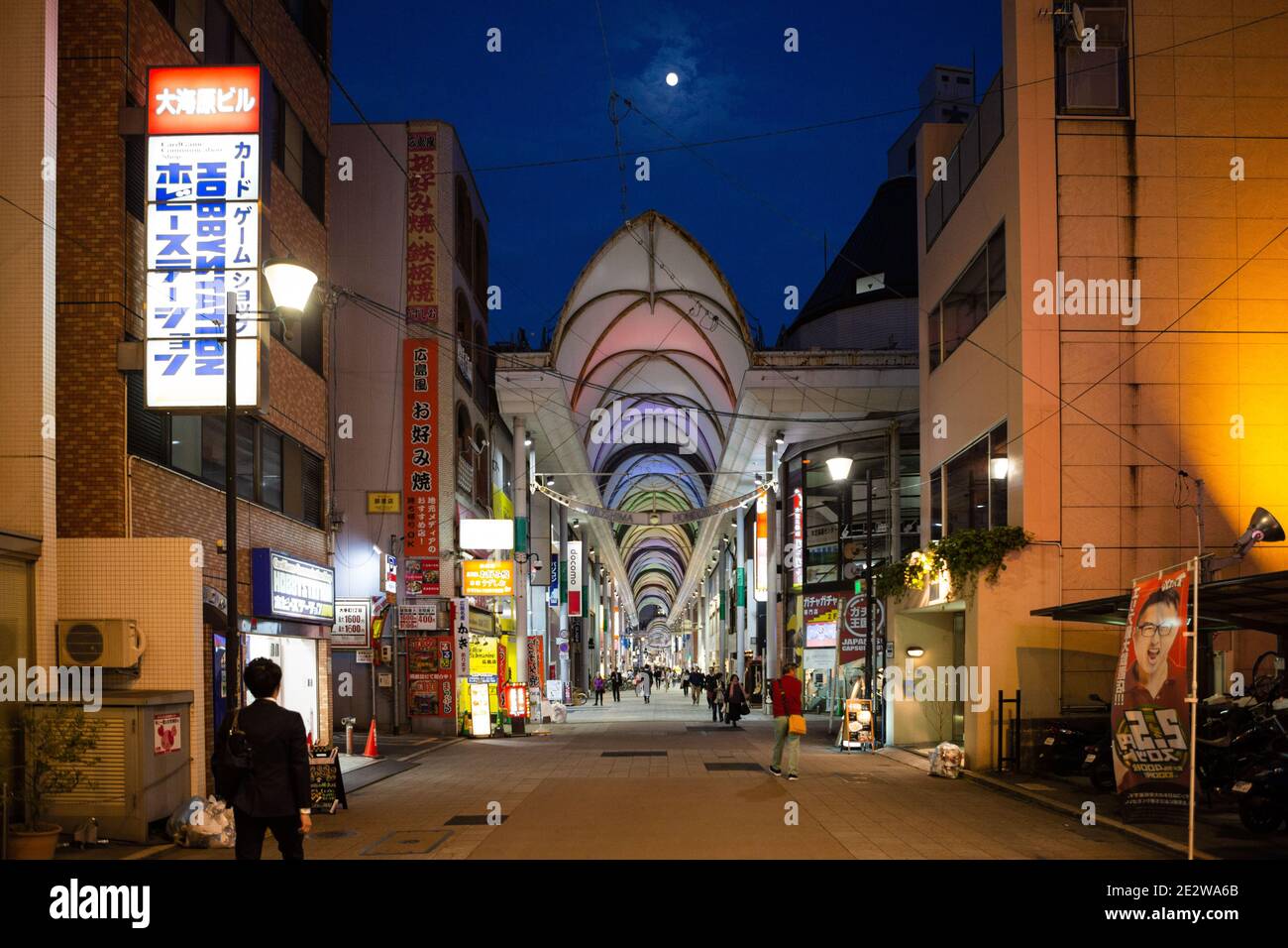 Hondori St, Hiroshima, Japan, zeigt einen überdachten Gang mit Geschäften von außen, mit dem Mond im Himmel oben. Stockfoto