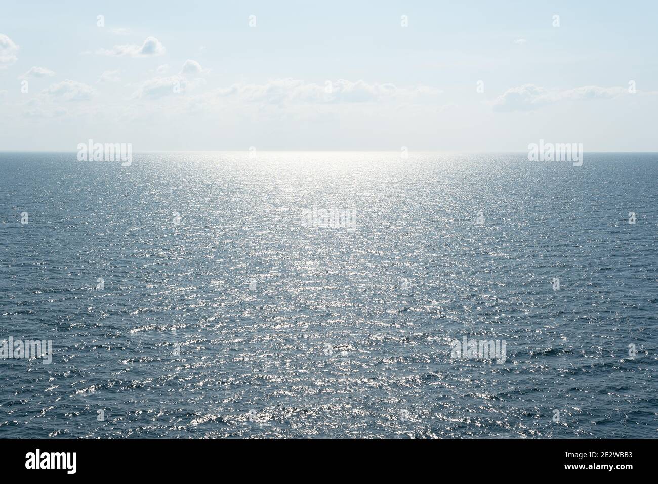 Minimalistisches Meeresbild mit Sonnenreflexion auf den Wellen und Blick auf die Skyline Mit Kopierplatz für Text Stockfoto