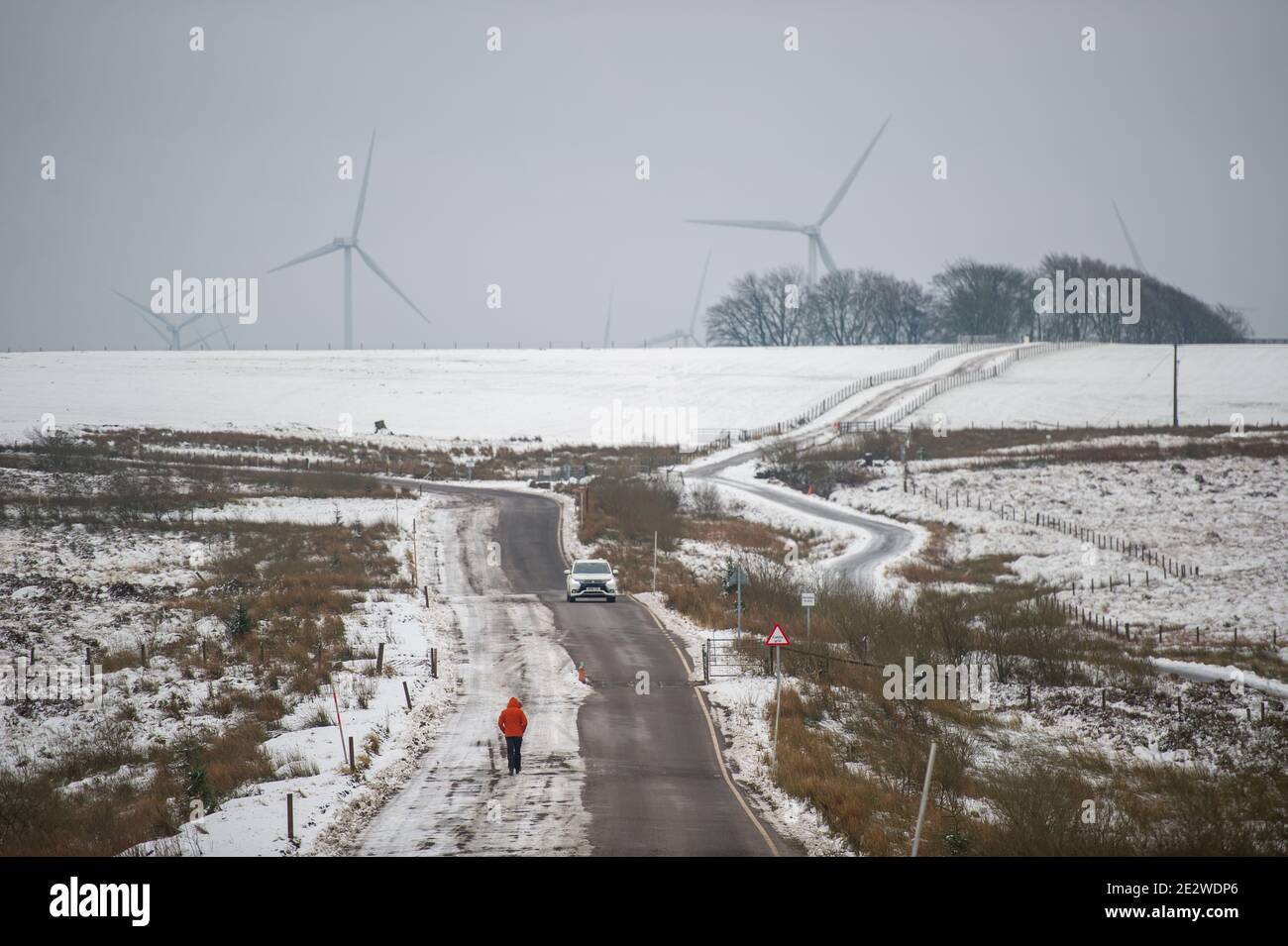 Windpark Whitelee, Eaglesham, Schottland, Großbritannien. Januar 2021. Im Bild: Menschen, die auf der schneebedeckten Moorlandschaft auf der Windfarm Whitelee spazieren und joggen, nehmen ihre tägliche Bewegung an, da Schottland aufgrund der Coronavirus (COVID-19) Pandemie noch in Phase 4 gesperrt ist. Windpark Whitelee unter einem Teppich aus Schnee gesehen, der aufgrund seiner Lage auf dem höheren Boden immer noch auf dem Boden liegt. Es ist beliebt bei Menschen, die ihre Lockdown tägliche Bewegung. Quelle: Colin Fisher/Alamy Live News Stockfoto