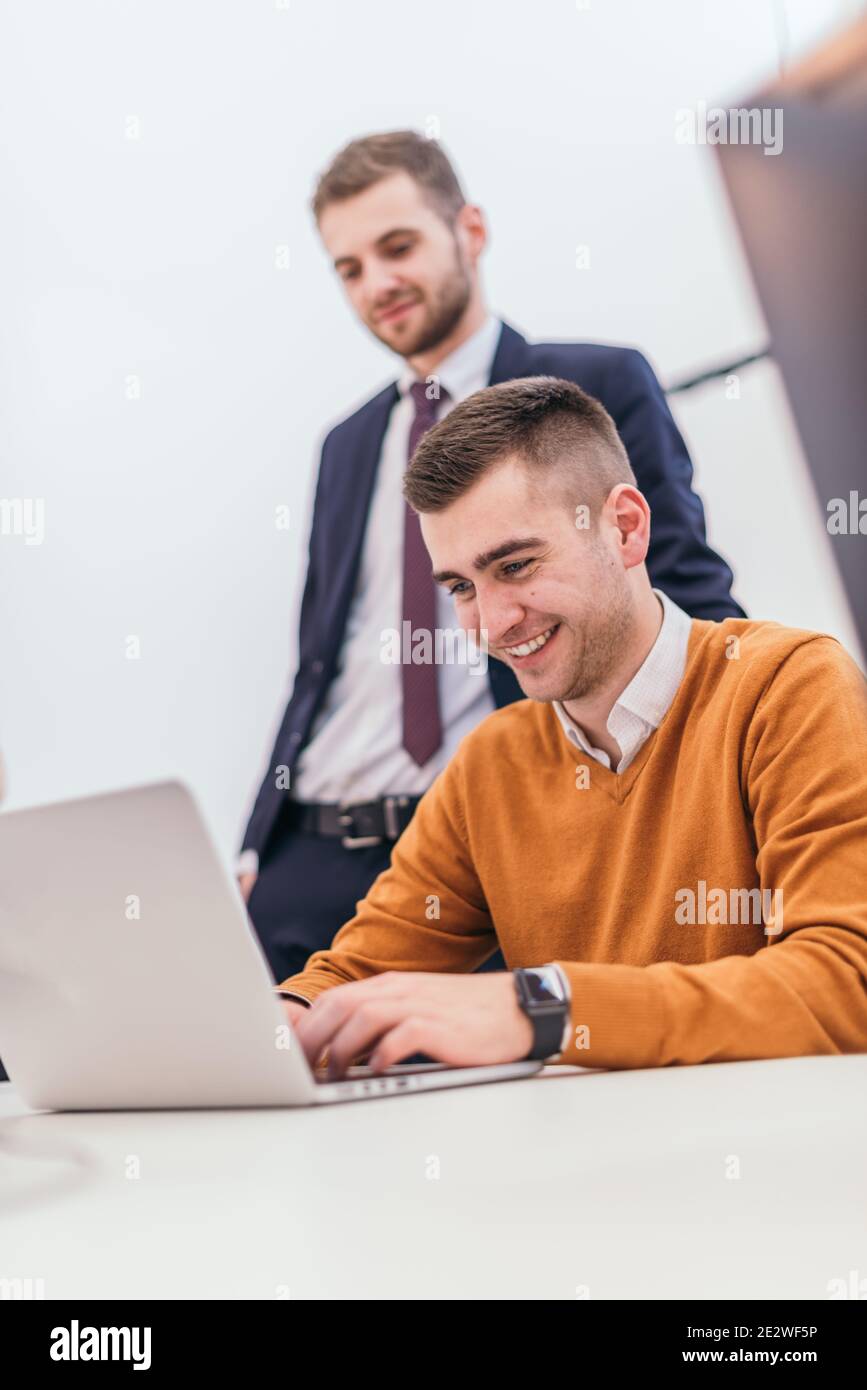 Bild eines Geschäftsmannes, der an einigen finanziellen Details arbeitet, mit einem geeigneten Manager, der neben ihm steht Stockfoto