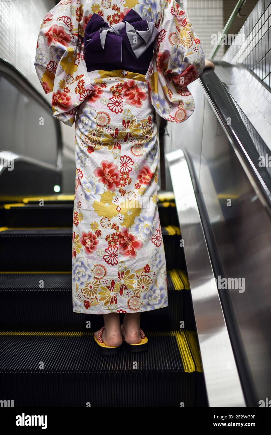 Junge Frau mit japanischem Kimono und geta-Schuhen in der Rolltreppe der U-Bahn-Station, Blick von hinten Stockfoto