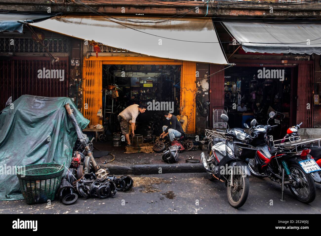 Zwei Männer arbeiten an der Überholung von Autoteilen in einem kleinen Laden in Talat Noi Stockfoto