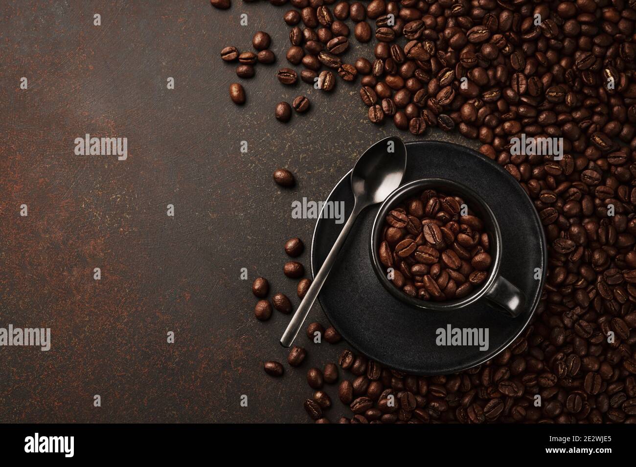 Schwarze Tasse Kaffee mit gerösteten Bohnen auf steinernem Hintergrund. Draufsicht mit Platz zum Kopieren von Text Stockfoto