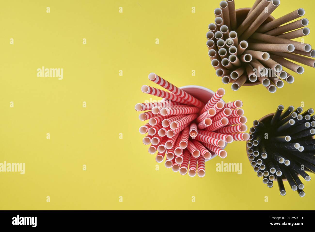 Trinkröhrchen rot und braun aus Papier und Maisstärke, biologisch abbaubares Material und Öko Papiergläser auf gelbem und grauem Trendfarbe 2021 Hintergrund Stockfoto