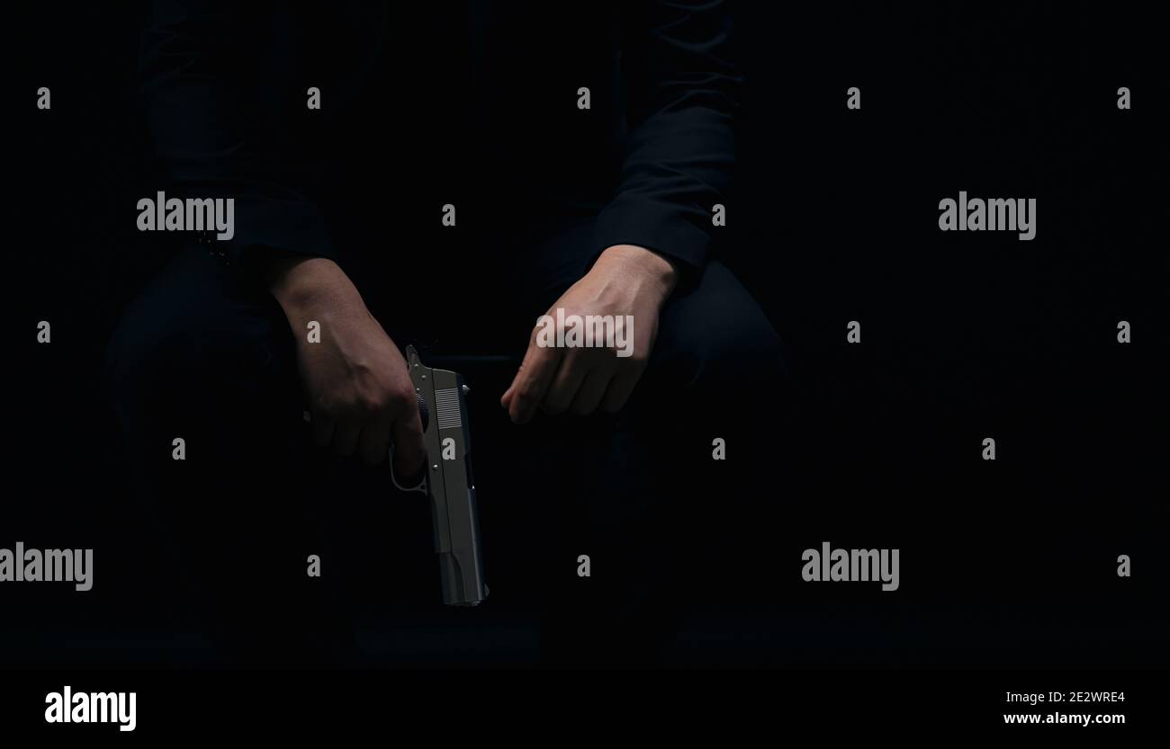 Gangster hält Waffe auf schwarzem Hintergrund Stockfoto
