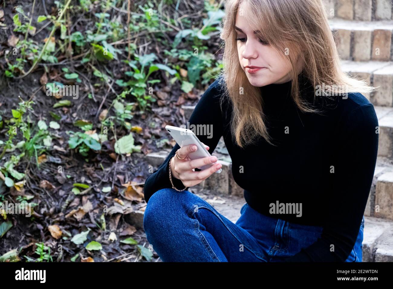 Junge Frau, die am Telefon im Park unzufrieden, SMS-Nachrichten, mit Anwendungen Stockfoto