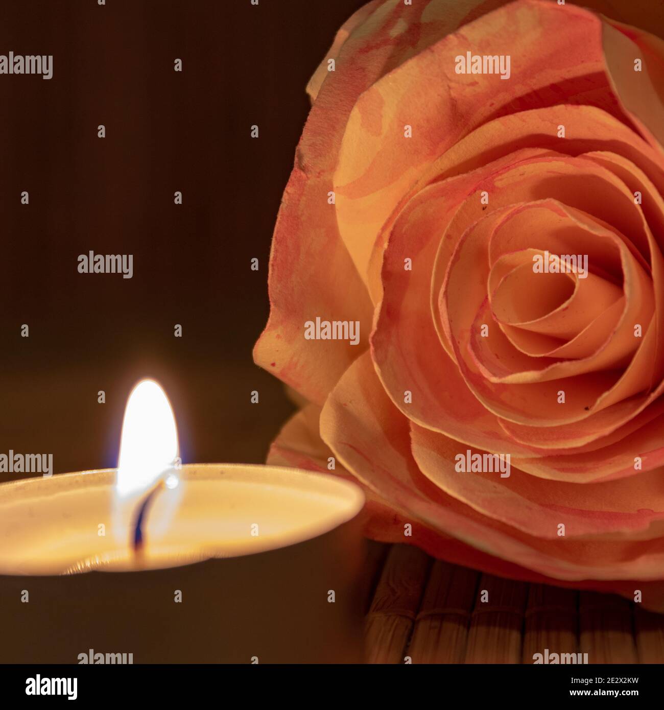 Nahaufnahme der Rosenblüte aus Papier und Kerze auf Holztisch mit Kopierraum. Stockfoto