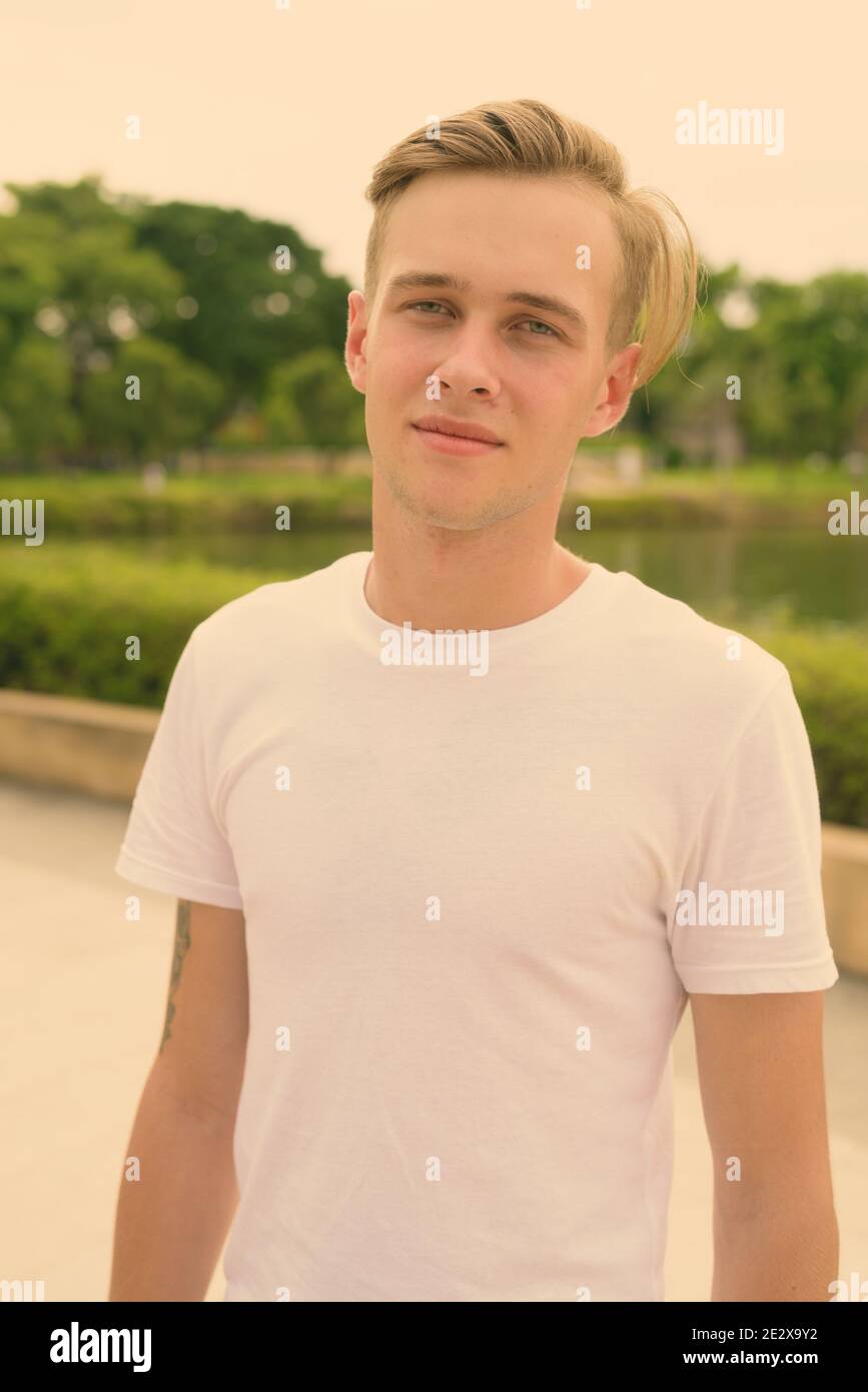 Junger stattlicher Mann mit blonden Haaren Entspannung im Park Stockfoto