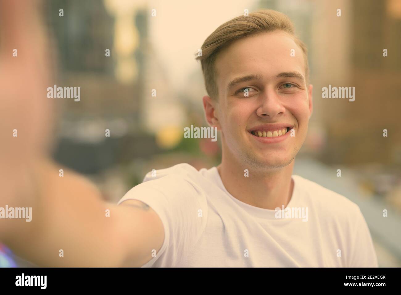 Junger stattlicher Mann mit blonden Haaren gegen den Blick auf die Stadt Stockfoto