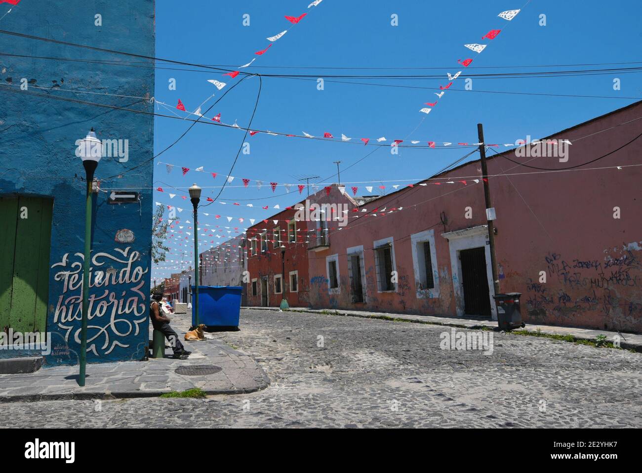 Ein Einheimischer in einer zentralen Kopfsteinpflasterstraße mit den alten Kolonialhäusern und den bunten lokalen Festflaggen in Puebla de Zaragoza, Mexiko. Stockfoto