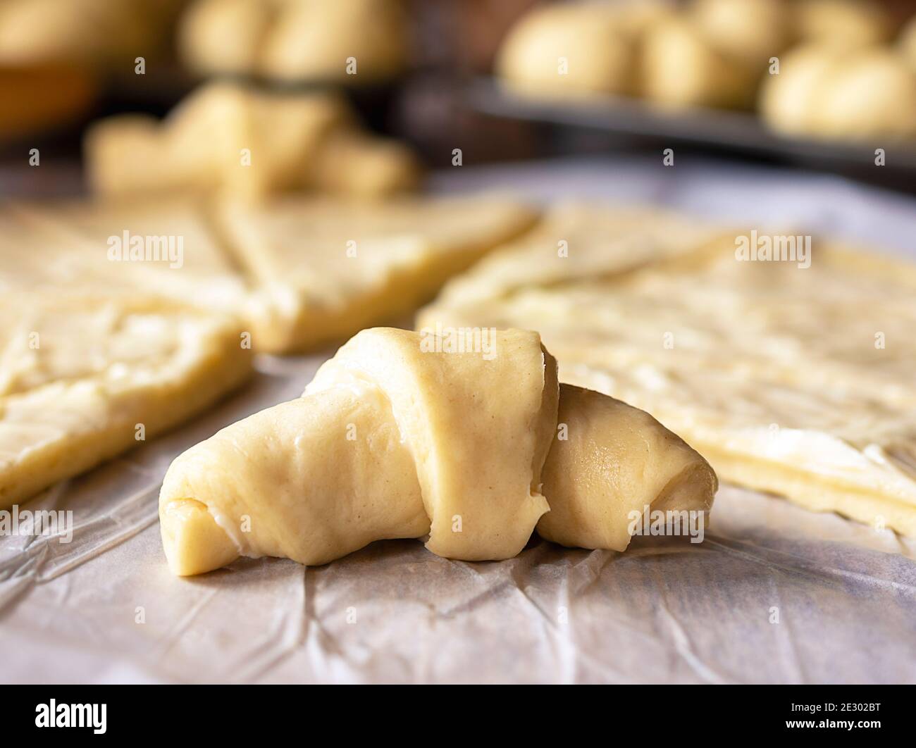 Nahaufnahme der Sichelrolle. Für Halbmondrollen wurde der Hefeteig ausgerollt. Der Teig wurde in Butter gewaschen. Zusätzliche Rollen im Rücken Stockfoto