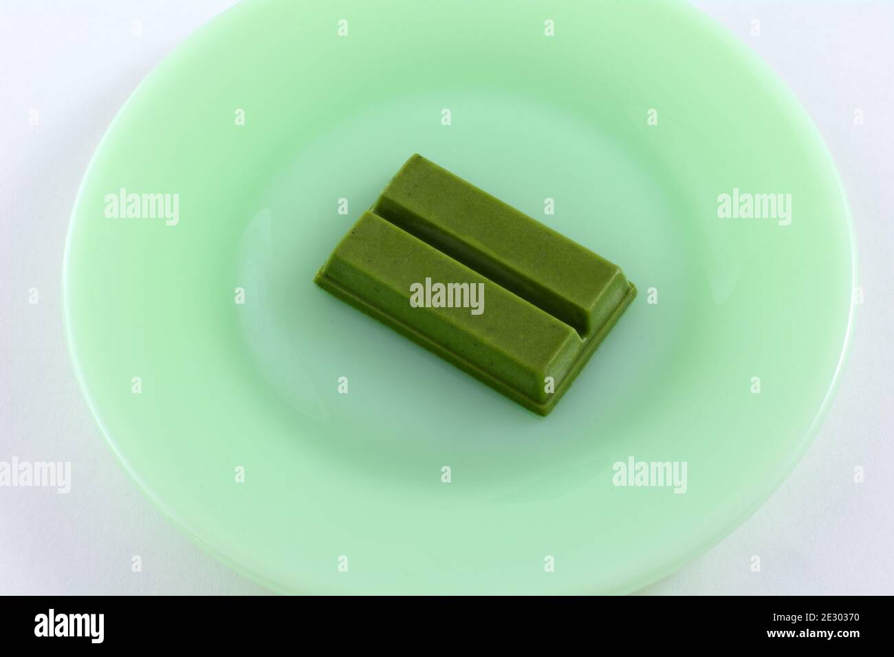 Schokoriegel mit dunkelgrüner Schokolade und Matcha-Geschmack auf grünem Teller Auf weißem Hintergrund Stockfoto