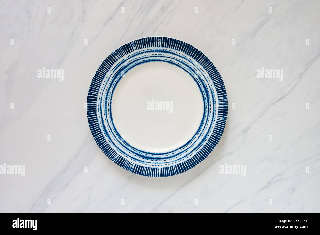 Leere Platte mit blauem runden Design auf Marmor-Tischplatte, Lebensmittel Hintergrund lag flach Bild mit viel Platz für Text kopieren. Stockfoto