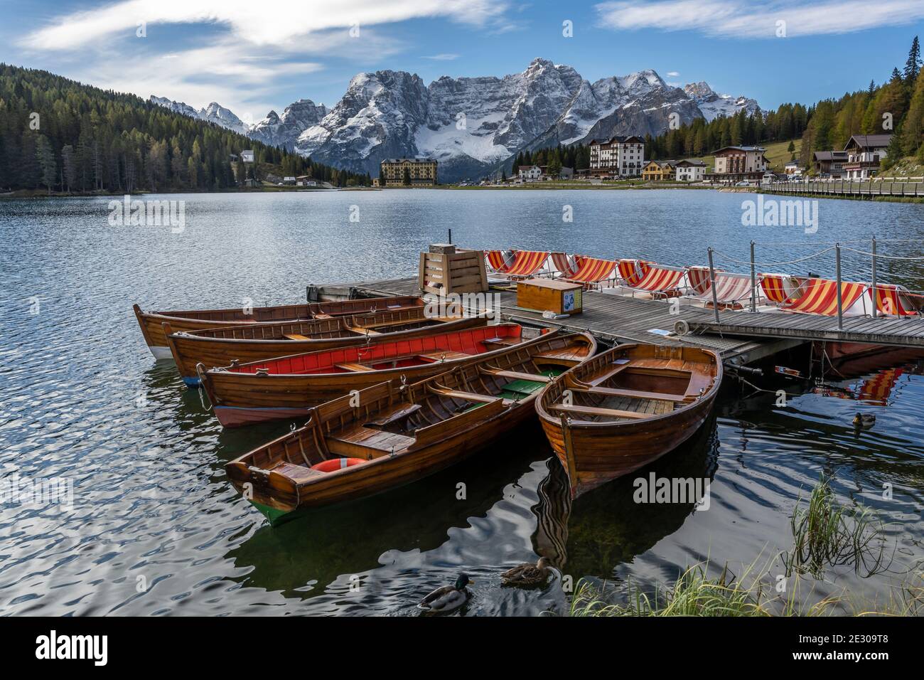 Misurina, Italien - 8. Oktober 2020: Der Misurina See mit touristischen Booten und Hotels und verschneiten Bergen der Dolomiten im Hintergrund, im Herbst, Stockfoto