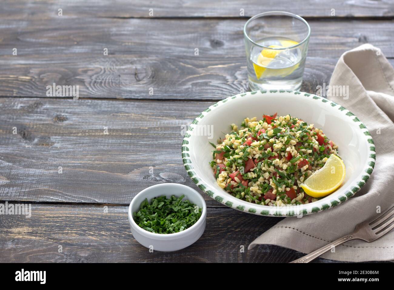 Tabbouleh, traditioneller arabischer Salat aus Bulgur, Petersilie und Tomaten auf einem Holztisch mit freiem Platz. Köstliche Diät-Essen Stockfoto