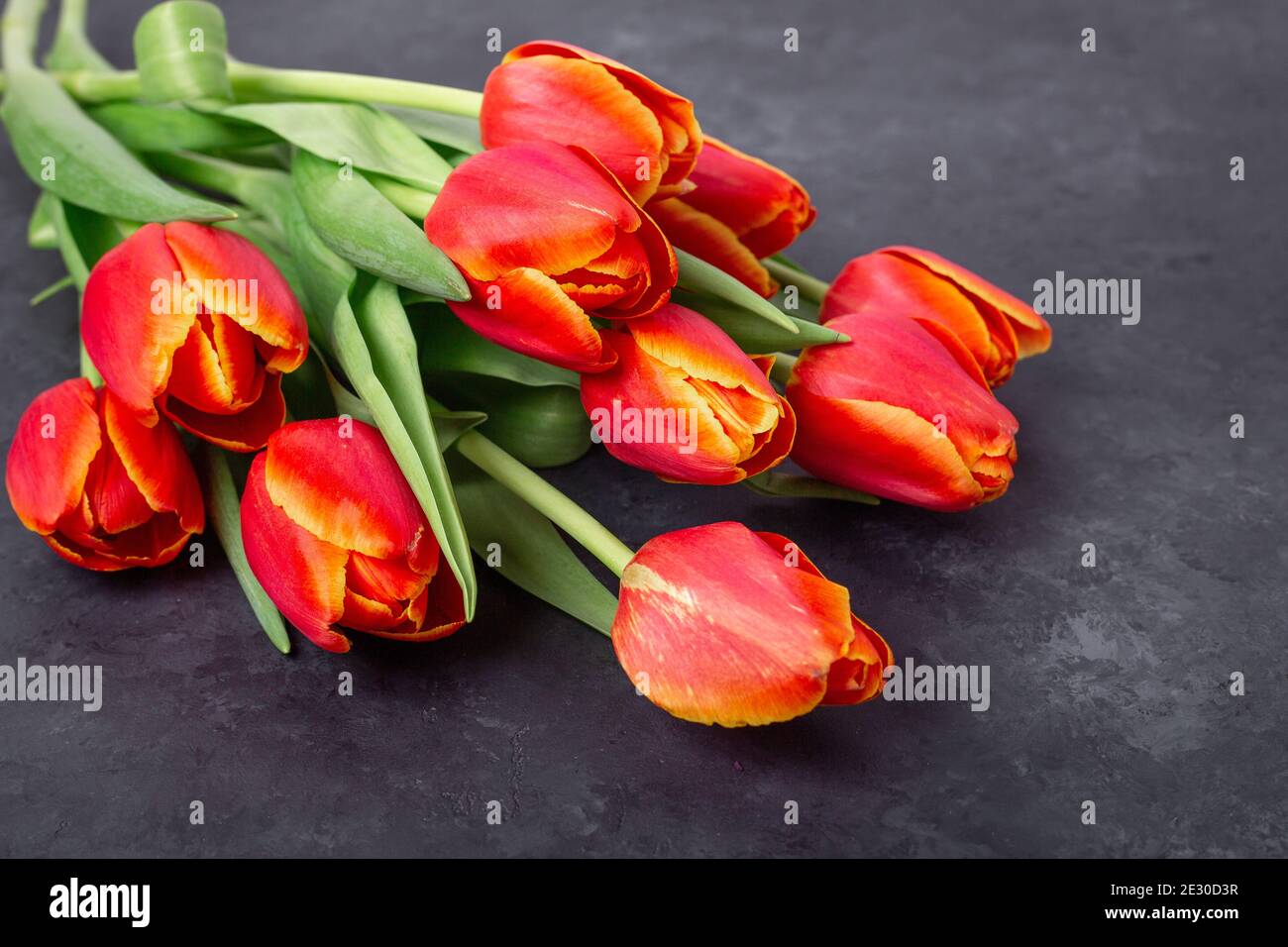 Bouquet von roten Tulpen auf einem dunklen Steintisch. Frühlingshintergrund - Bild Stockfoto
