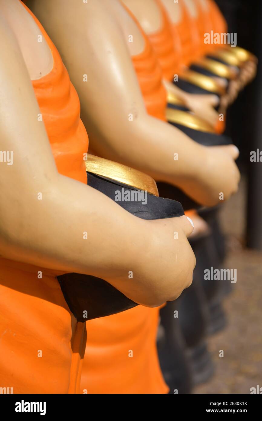 Ein Seitenprofil perspektivische Ansicht von Statuen von buddhistischen Mönchen tragen Safran Roben und halten Almosenschüsseln. Stockfoto