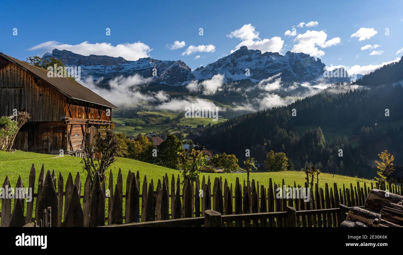 Badia, Alta Adige in der Nähe von Corvara Tal mit alten Scheune, Bauernhof und Wald mit den Dolomiten Berge mit Schnee im Hintergrund. Stockfoto