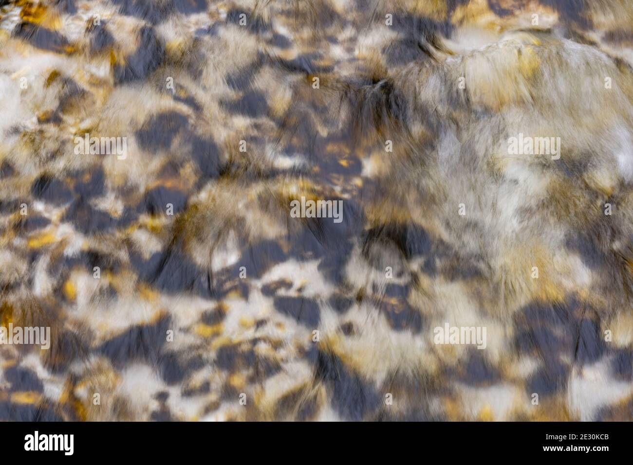 Wasserfluss in den alpen mit schwarzen und gelben Flecken von alten Blättern. Stockfoto