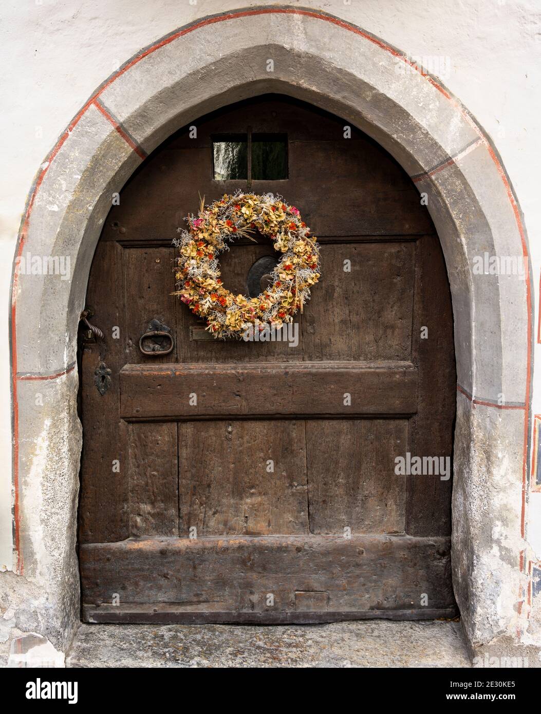 Herbstkranz mit dreisten Blumen auf einer alten Holztür. Stockfoto