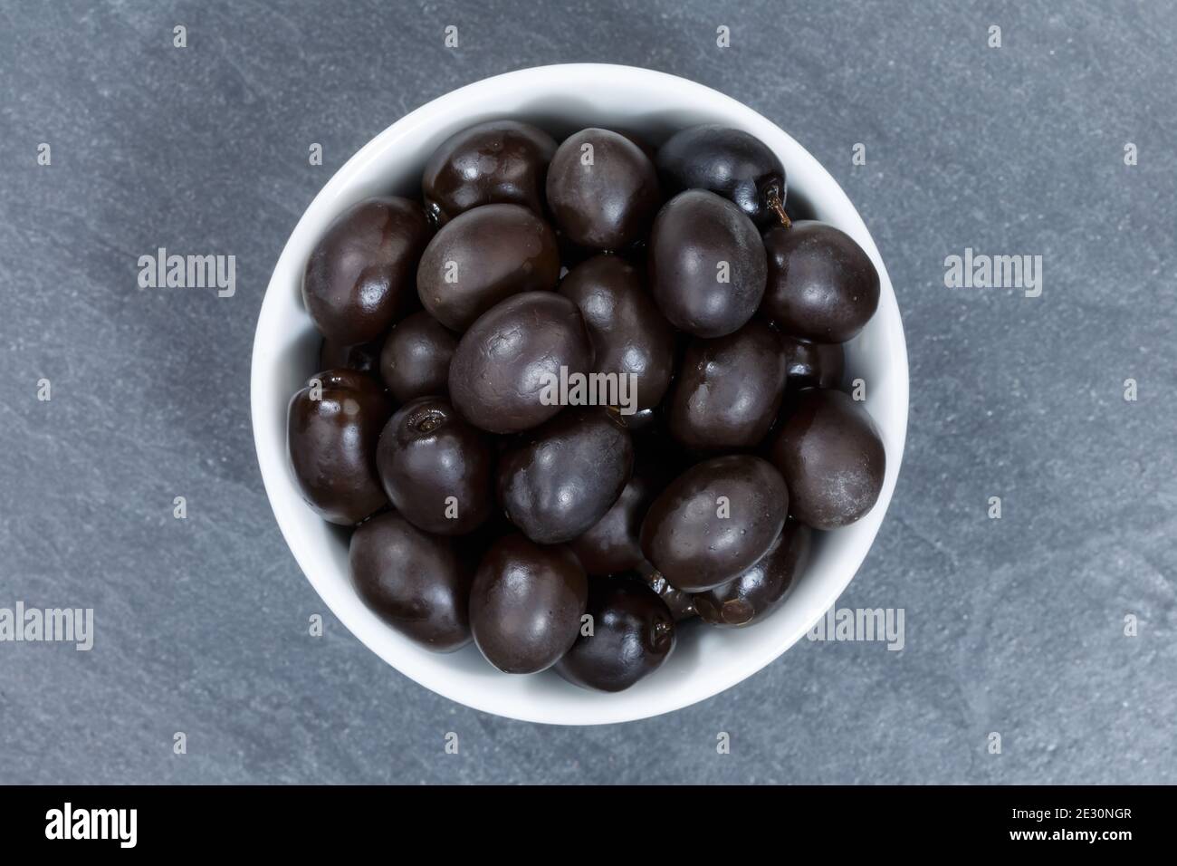Schwarze Oliven von oben Schüssel auf einem Schiefer Draufsicht Stockfoto