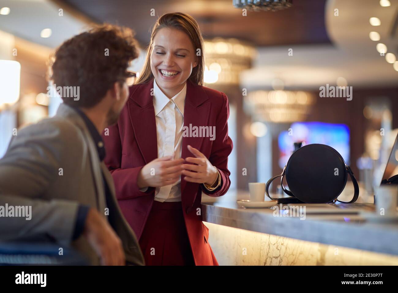 Junge Geschäftsfrau im Gespräch mit einem jungen männlichen Kollegen in einer Kaffeepause in entspannter Atmosphäre an der Bar. Business, Leute, Bar Stockfoto