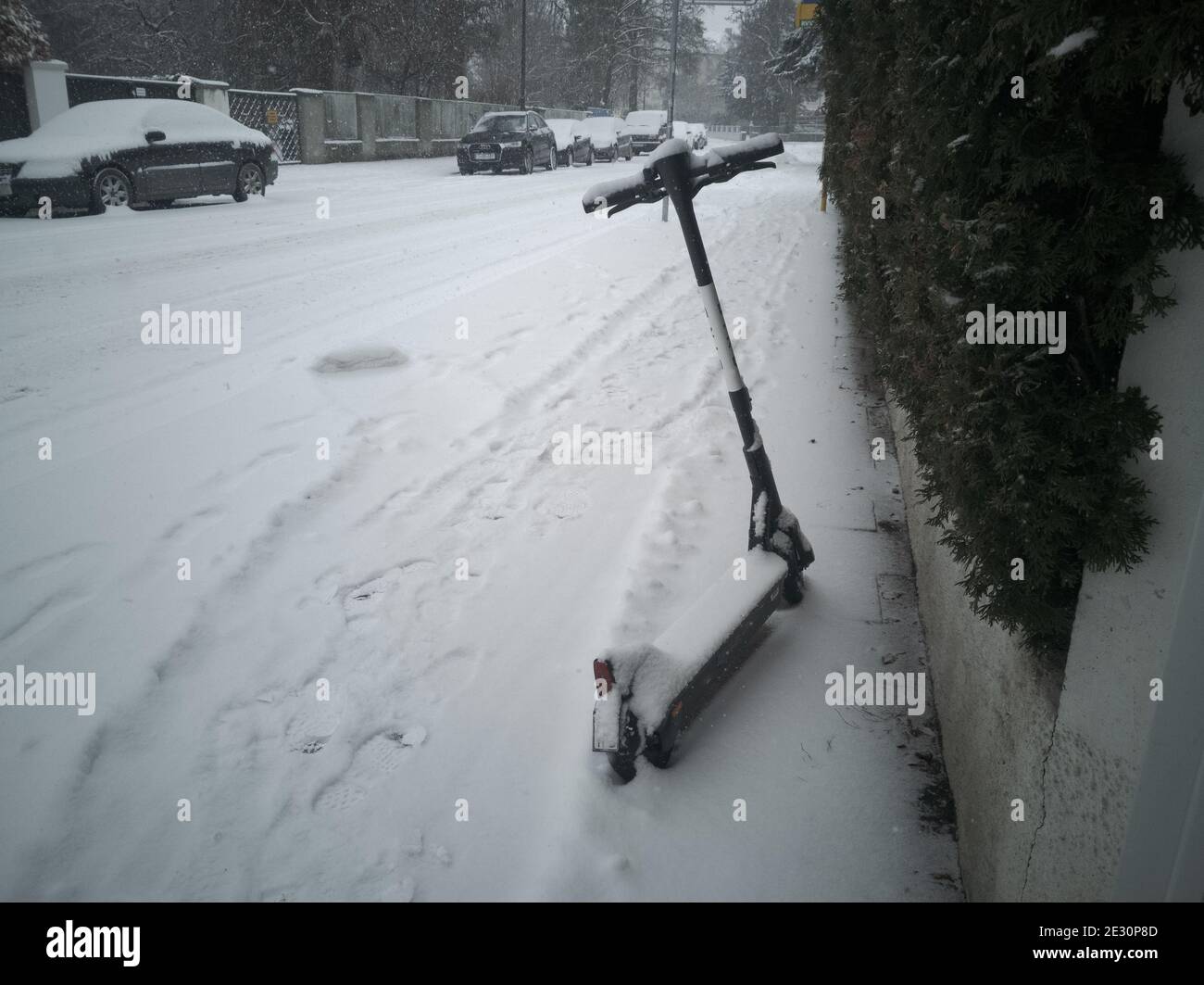 Verschneite Vermietung E-Scooter auf der Seite eines Bürgersteig stehen Im Winter bei starkem Schneefall Stockfoto