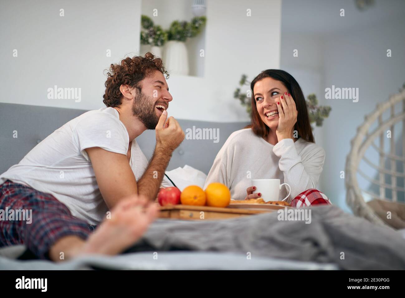 Ein junges verliebtes Paar, das romantische Momente beim Frühstück im Bett im Schlafzimmer hat. Liebe, Beziehung, zusammen Stockfoto