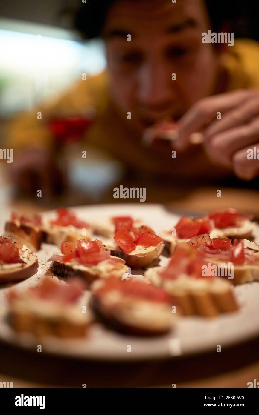 Ein junger Mann genießt Snacks in fröhlicher Atmosphäre in der Küche. Essen, Snacks, zu Hause Stockfoto