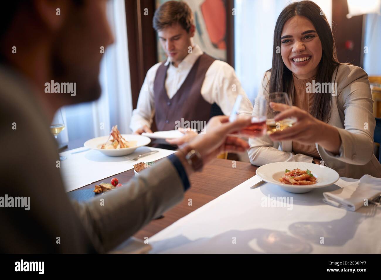 Kollegen toasten bei einem Business Lunch in fröhlicher Atmosphäre im Restaurant. Business, Restaurant, Mittagessen Stockfoto