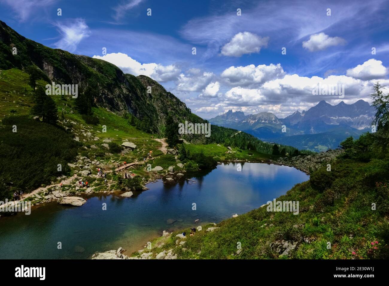 Wunderschöner Bergsee mit vielen bunten Wanderern am Ufer Im Sommer Stockfoto