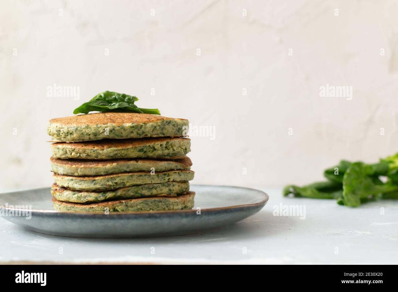 Spinat- und Bananenpfannkuchen mit grünen Blättern auf einem grauen Teller. Gesunde Ernährung Konzept. Speicherplatz kopieren. Horizontale Ausrichtung. Stockfoto