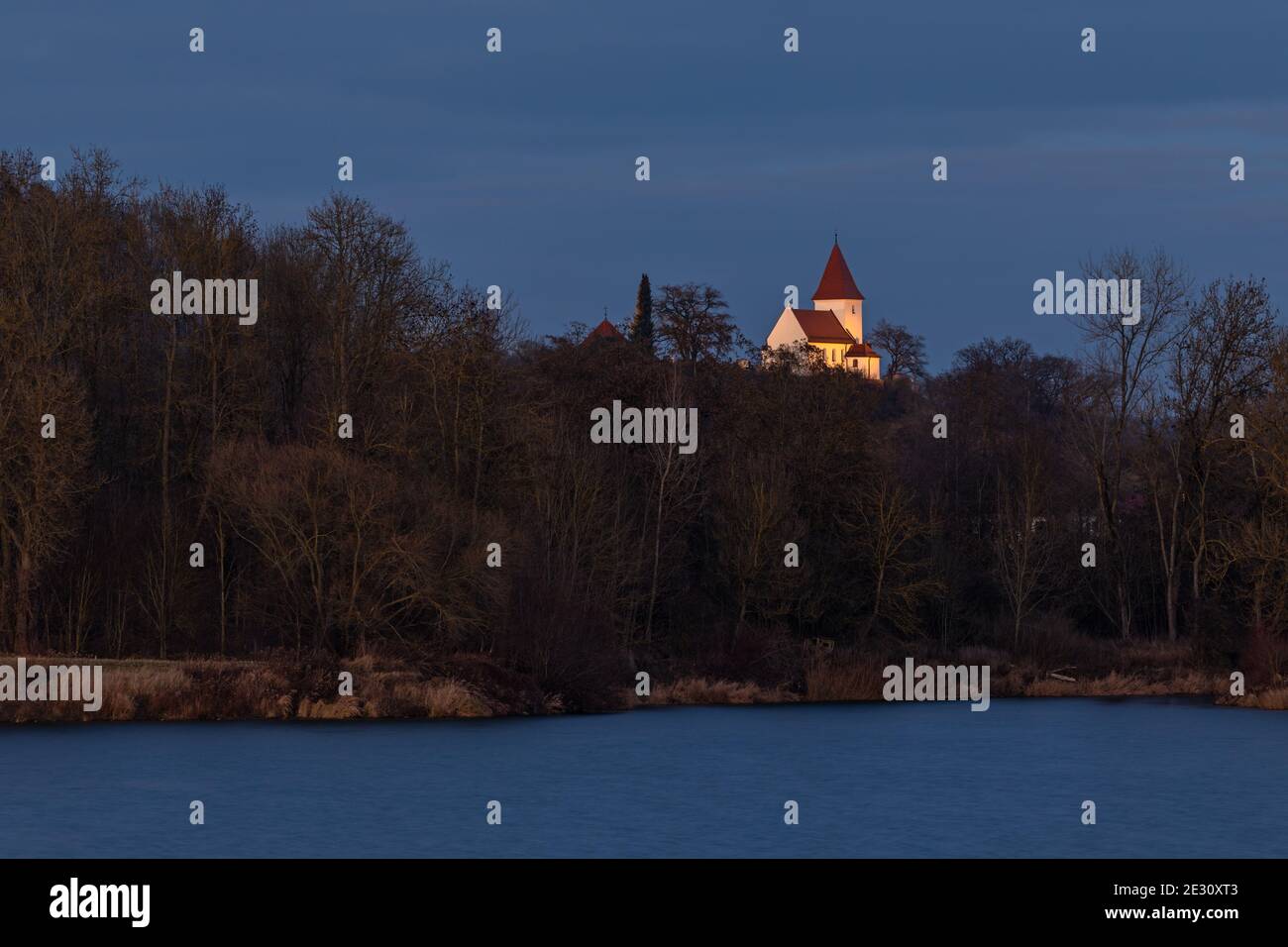 Beleuchtete Kirche von Schaefstall bei Donauwoerth über einem See in Bayern Stockfoto