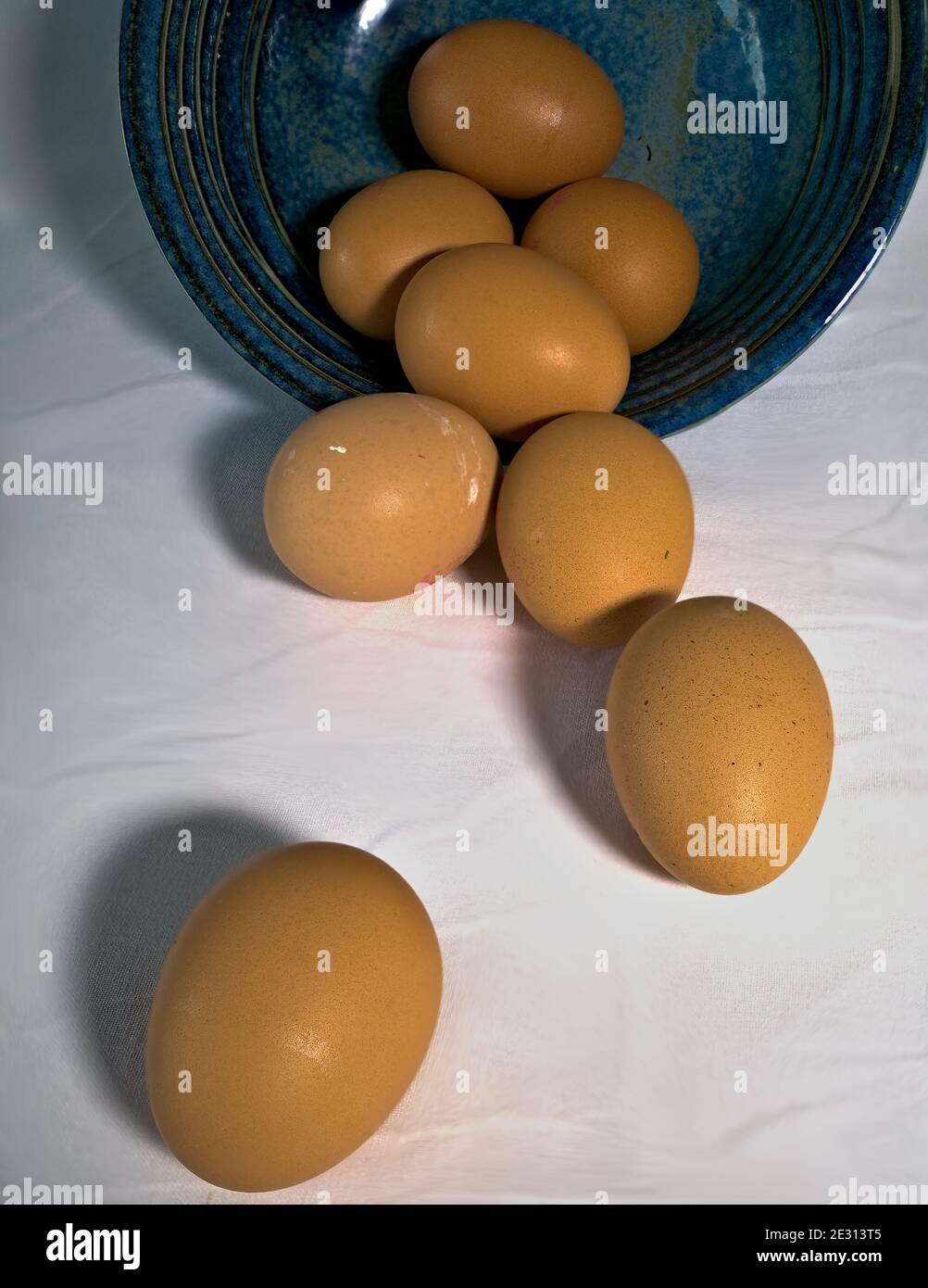 Eier, die aus einer blauen Schüssel verschüttet werden Stockfoto