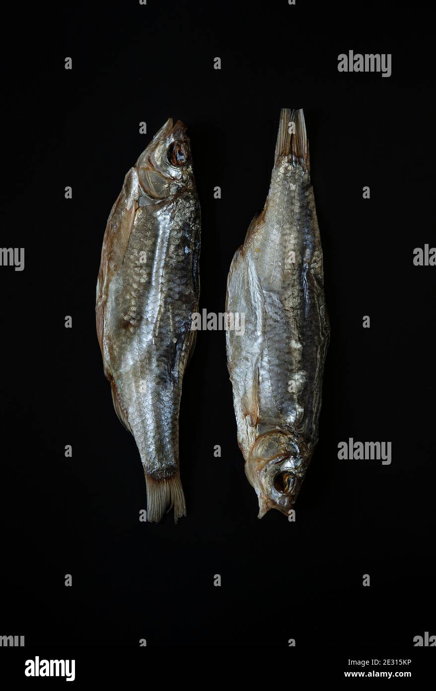 Nahaufnahme von oben Aufnahme von zwei getrockneten gesalzenen Fischen Auf schwarzem Hintergrund liegend Stockfoto