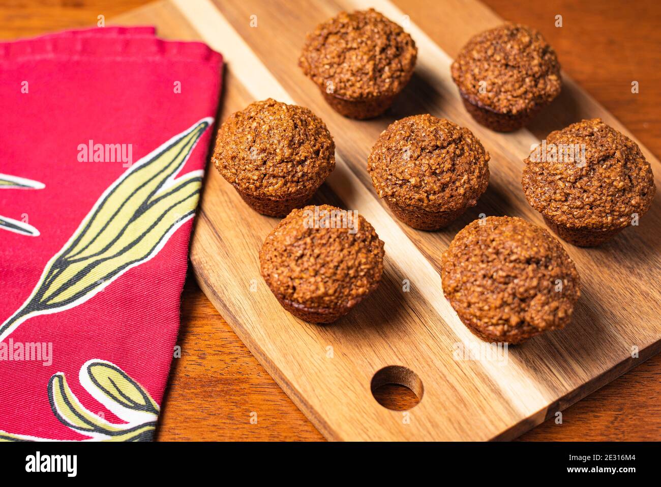 Bio-Kleie-Muffins in kreisförmigem Muster auf Holztablett mit Rote Serviette Stockfoto
