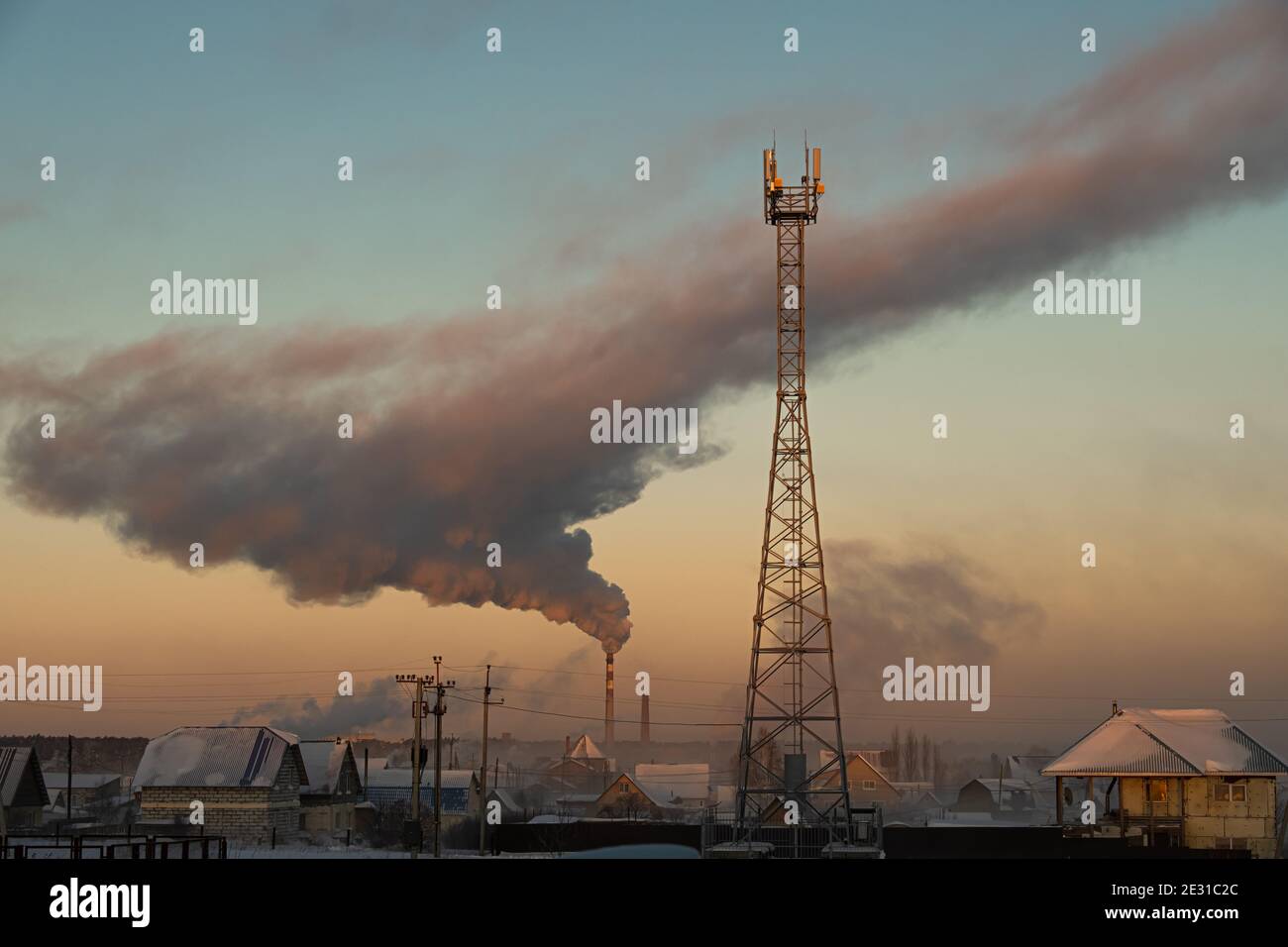 Rauch steigt aus dem Kamin des Kesselraums über der Stadt auf und der Zellenturm ist im Vordergrund. Russland, Nowosibirsk Region, Lufttemperatur -41 Stockfoto