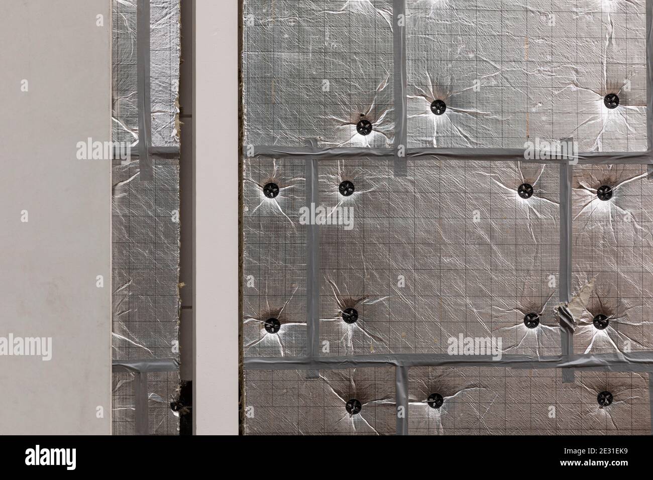 Silberne Aluminium-Isolierfolie an den Wänden, um ein energiesparendes Haus oder Gebäude zu schaffen. Umbau- und Sanierungskonzept Stockfoto