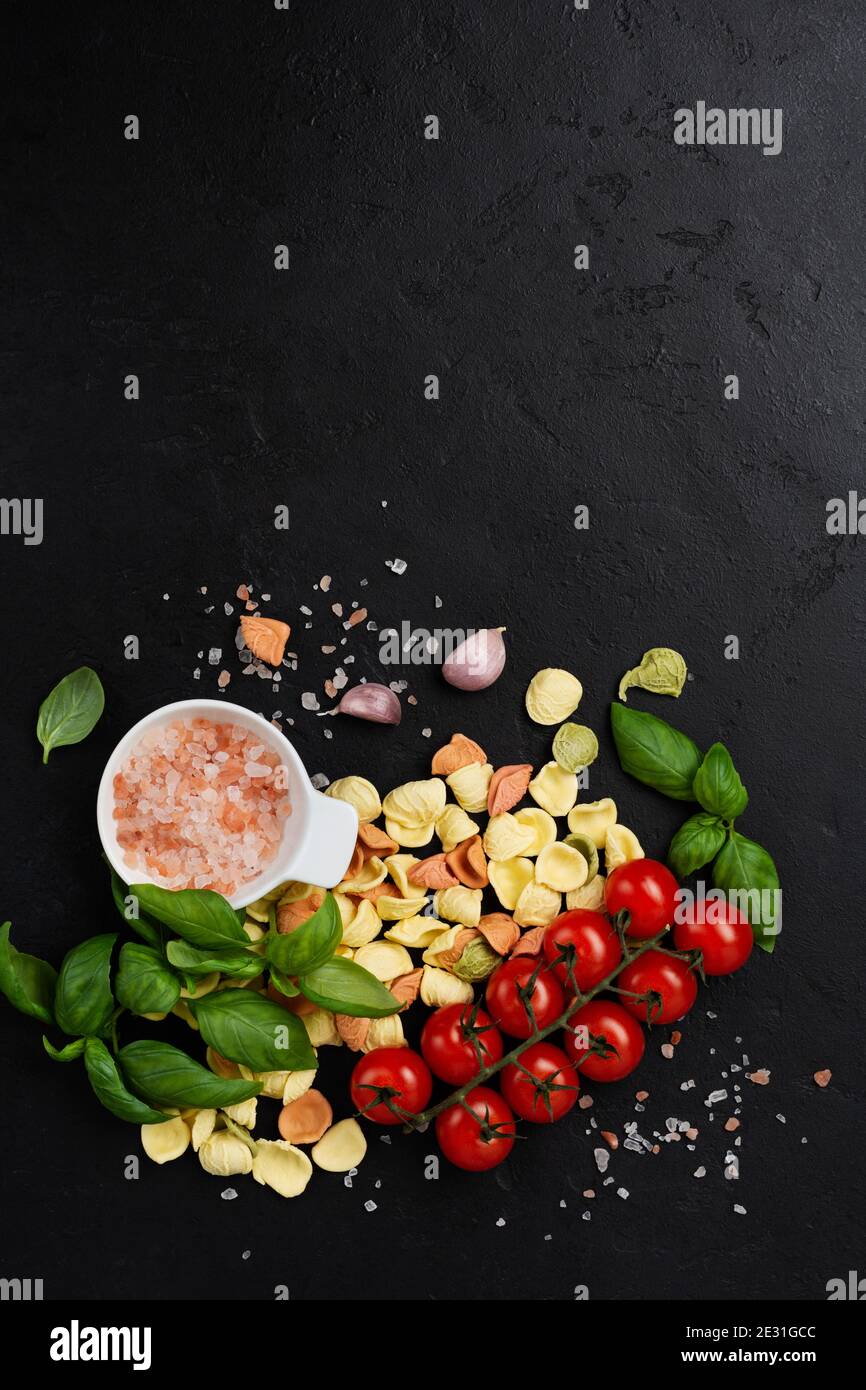 Italienische Pasta Orecchiette mit traditionellen Zutaten für die Zubereitung von Speisen auf schwarzem Hintergrund. Kulinarisches Essen Kochen Hintergrund. Draufsicht. Stockfoto